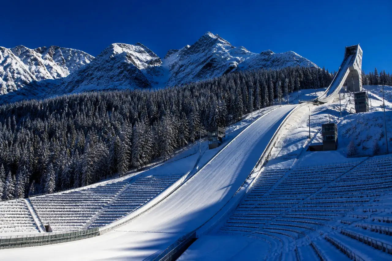 Grande trampolino da salto con gli sci in montagna, con la pista di lancio e l'ampio pendio di atterraggio innevato